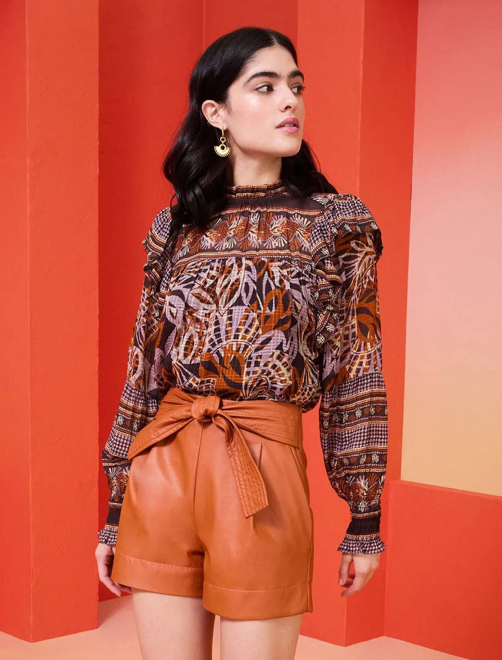 model wearing daphne blouse in orchid leaf tucked into orange leather shorts 