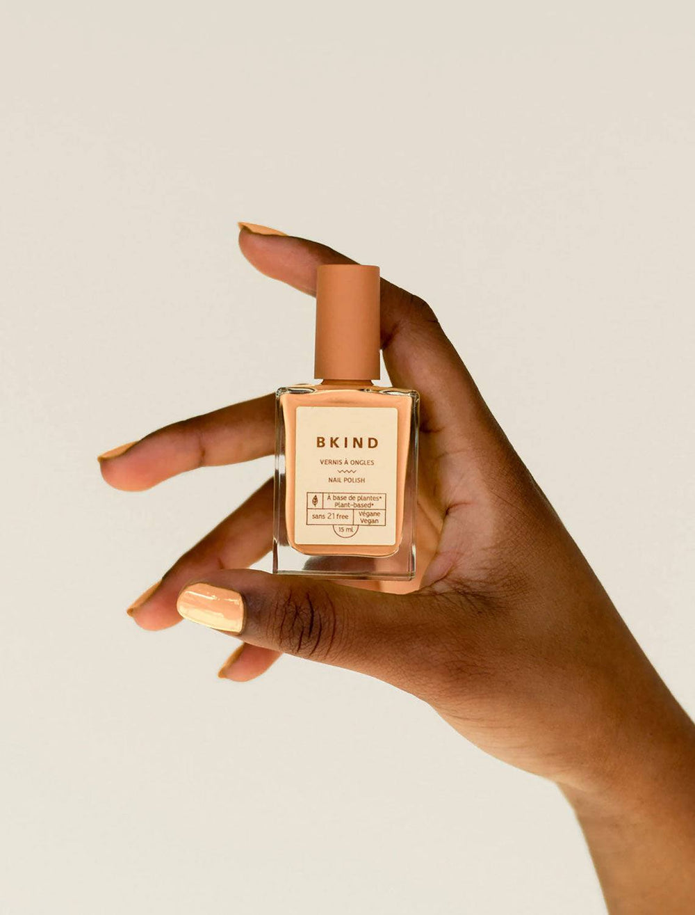 model holding bon colored nail polish bottle with bon color on nails