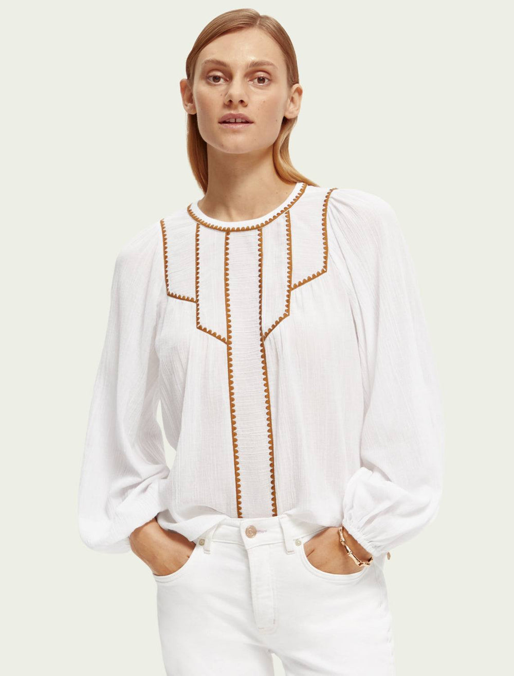 Model wearing Scotch & Soda's white patchwork bib blouse with embroidery.