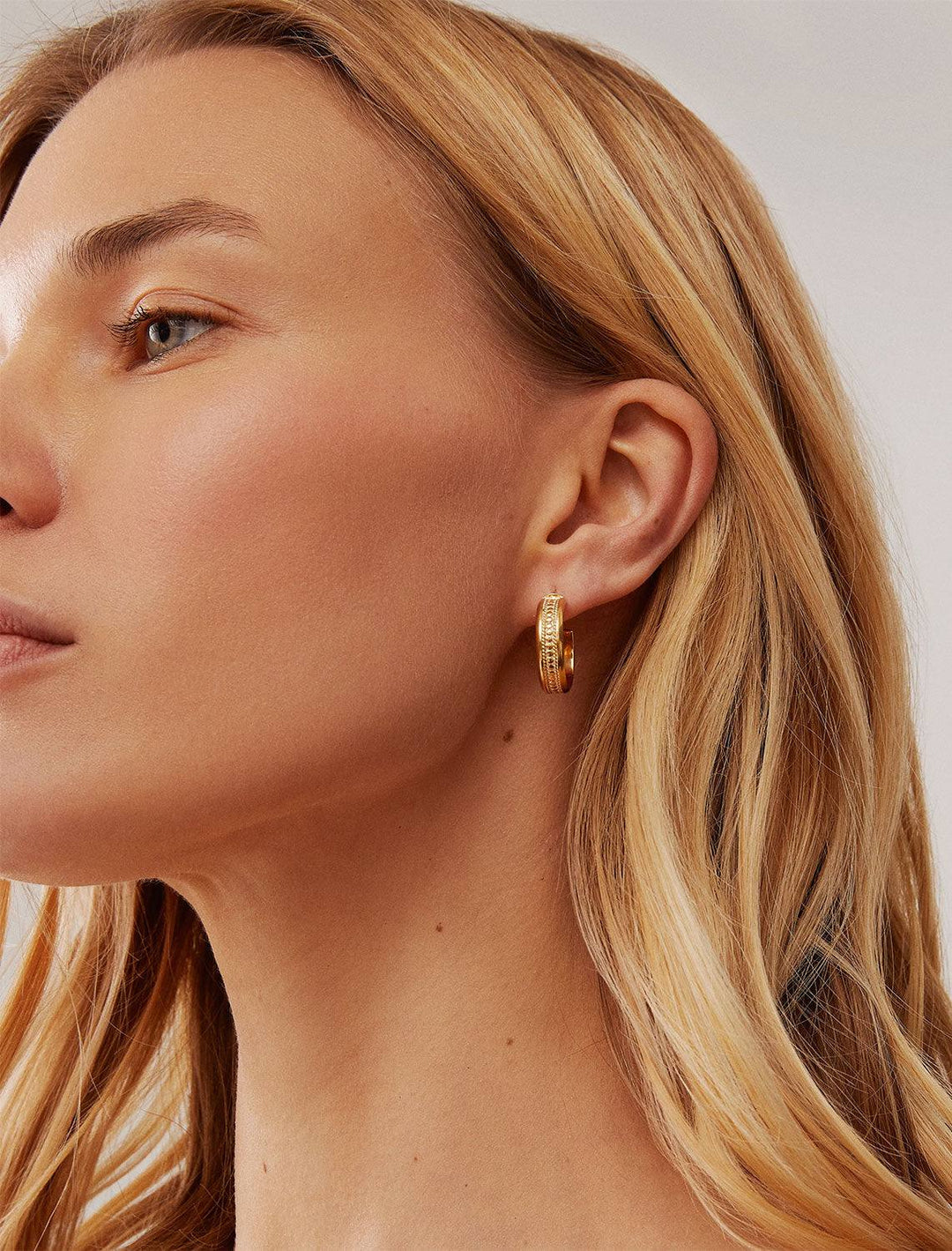 model wearing classic wide hoop earrings in gold