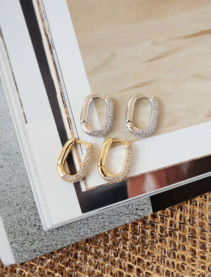 Stylized laydown of Luv AJ's pave chain link huggies in silver.