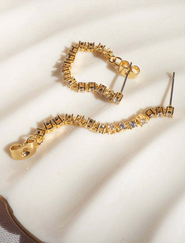 Stylized laydown of Luv AJ's ballier chain studs in gold.