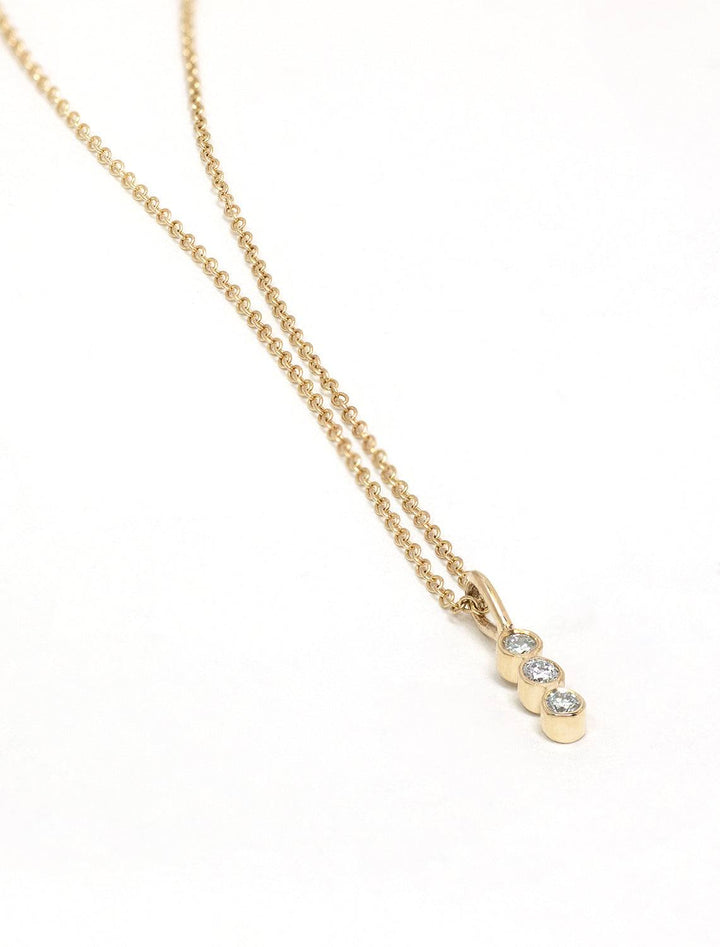 Close-up view of Zoe Chicco's 14k three stone diamond bar necklace.