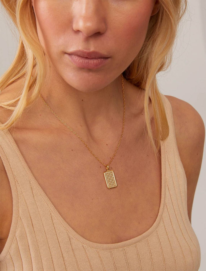 Model wearing Anna Beck's Rectangular Engravable Necklace in Two Tone.