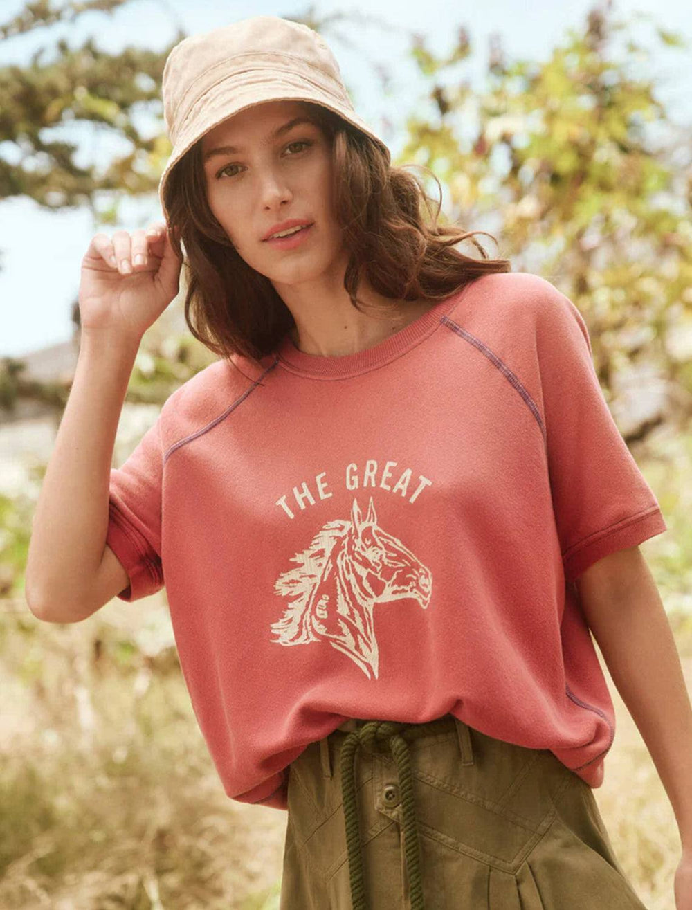 Model wearing The Great's short sleeve bronco sweatshirt in double washed red.