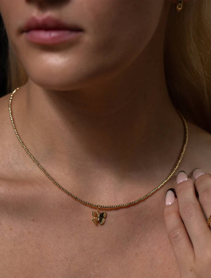 model wearing mini monarch necklace in gold