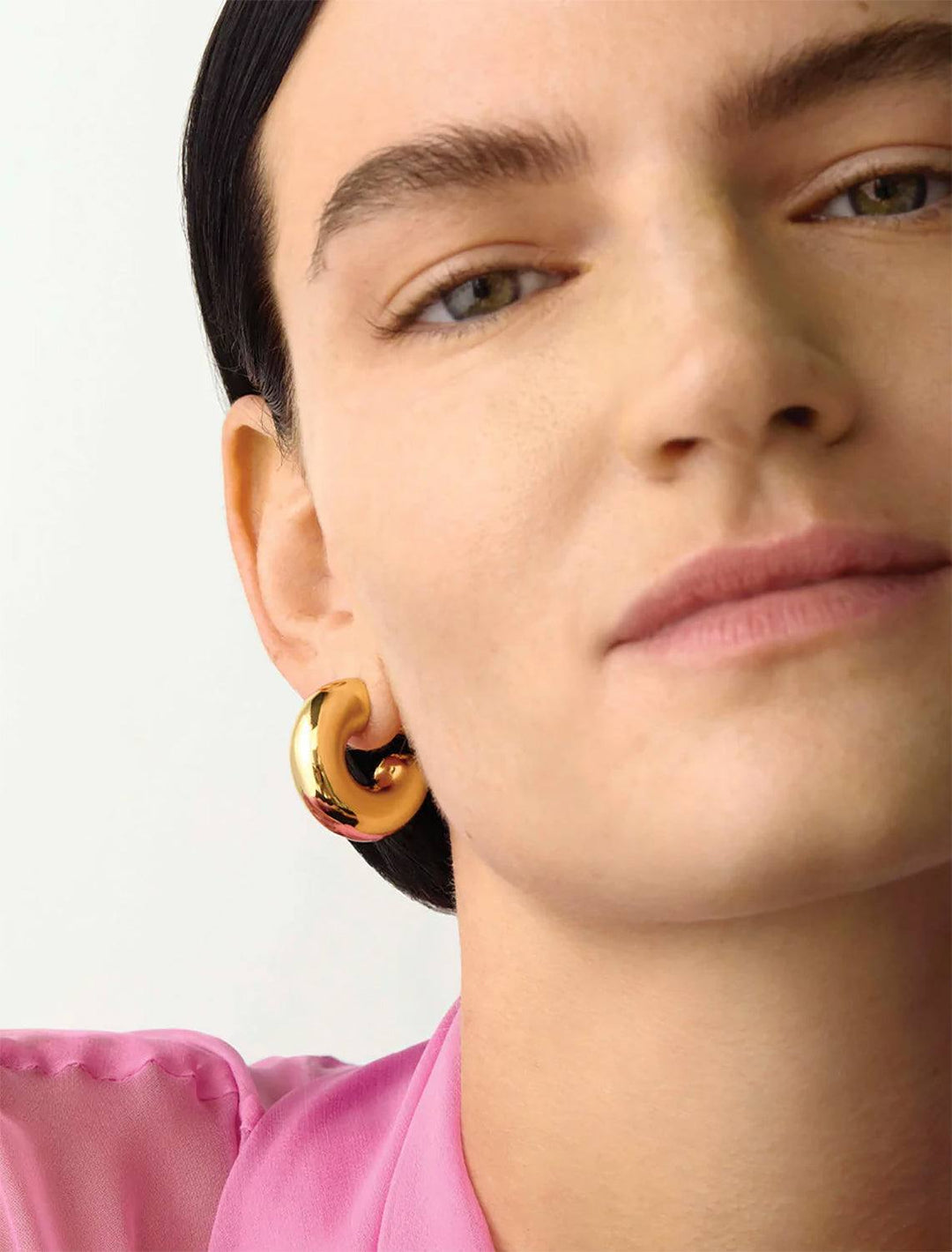 Model wearing Jenny Bird's Large Tome Hoops in 14K Gold-Dipped Brass. 