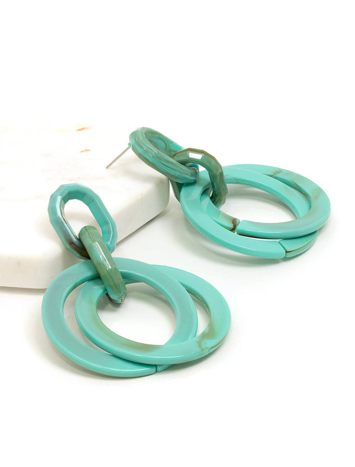 Stylized laydown of St. Armand's turquoise layered hoops.