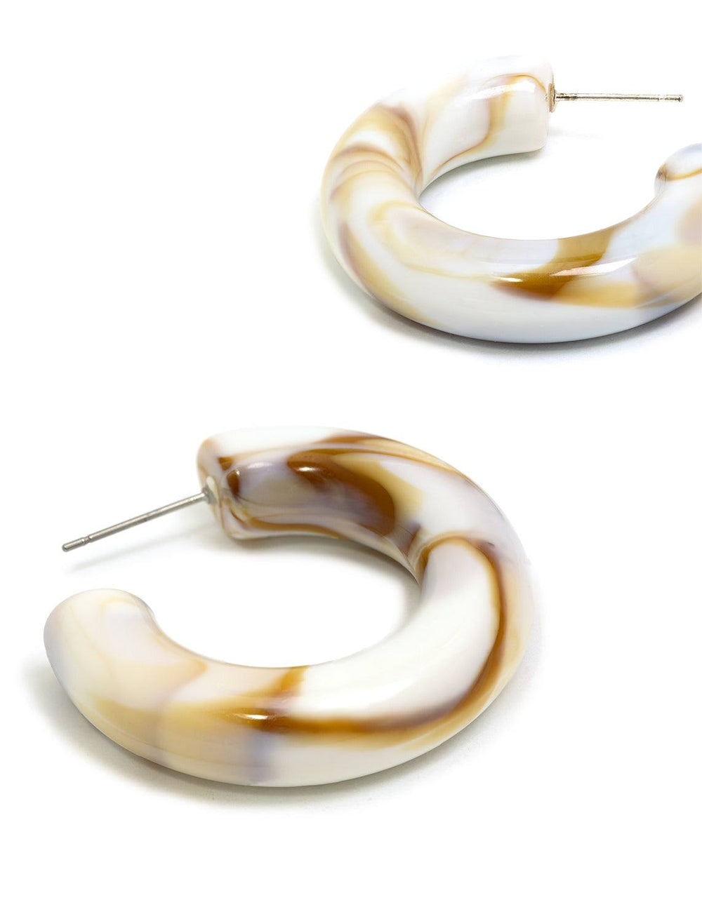 Stylized laydown of St. Armand's latte chunky lucite hoops.