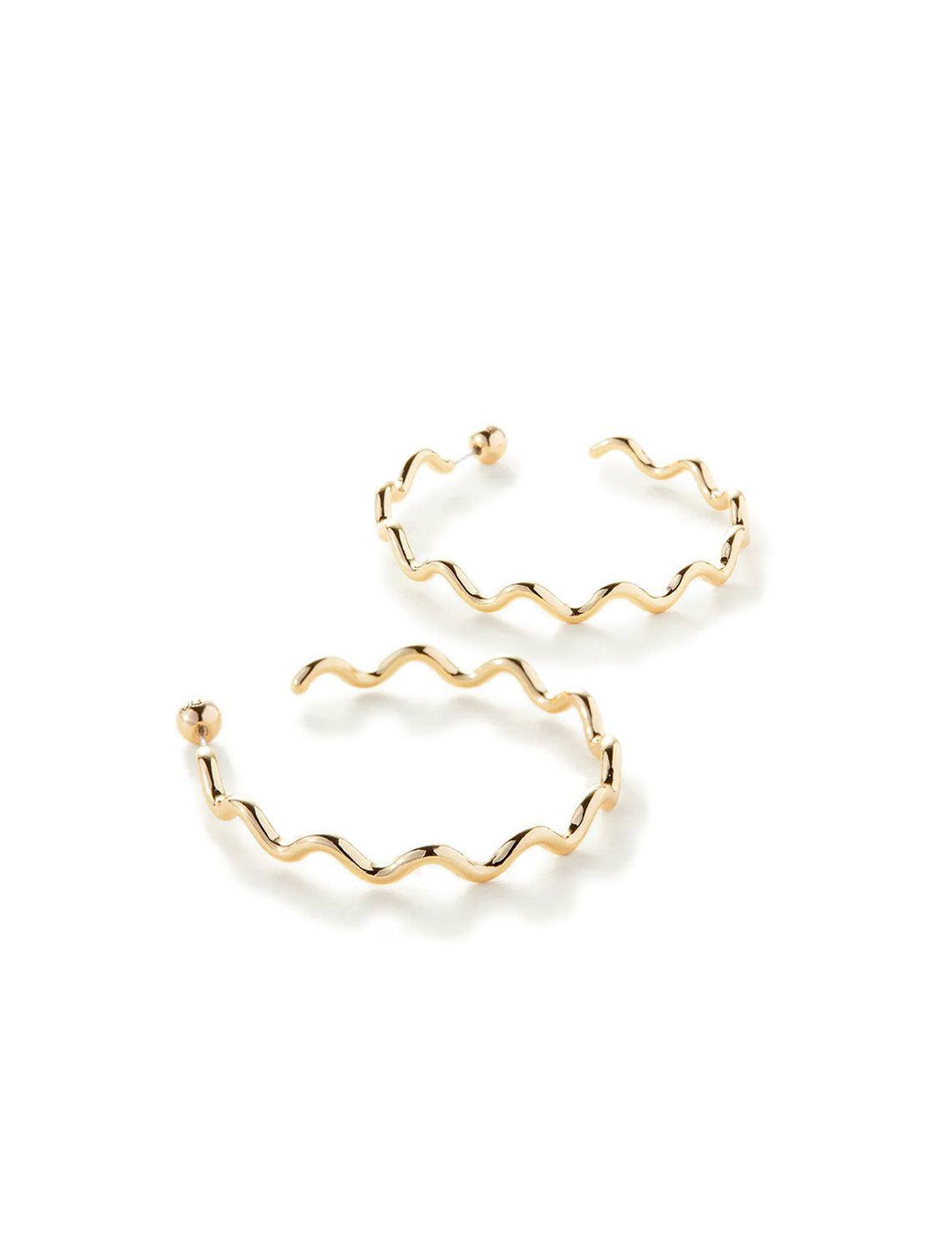 Stylized laydown of Jenny Bird's squiggle hoops in gold.
