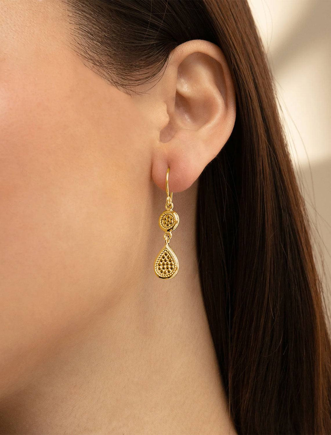 Model wearing Anna Beck's classic double drop earrings in gold.
