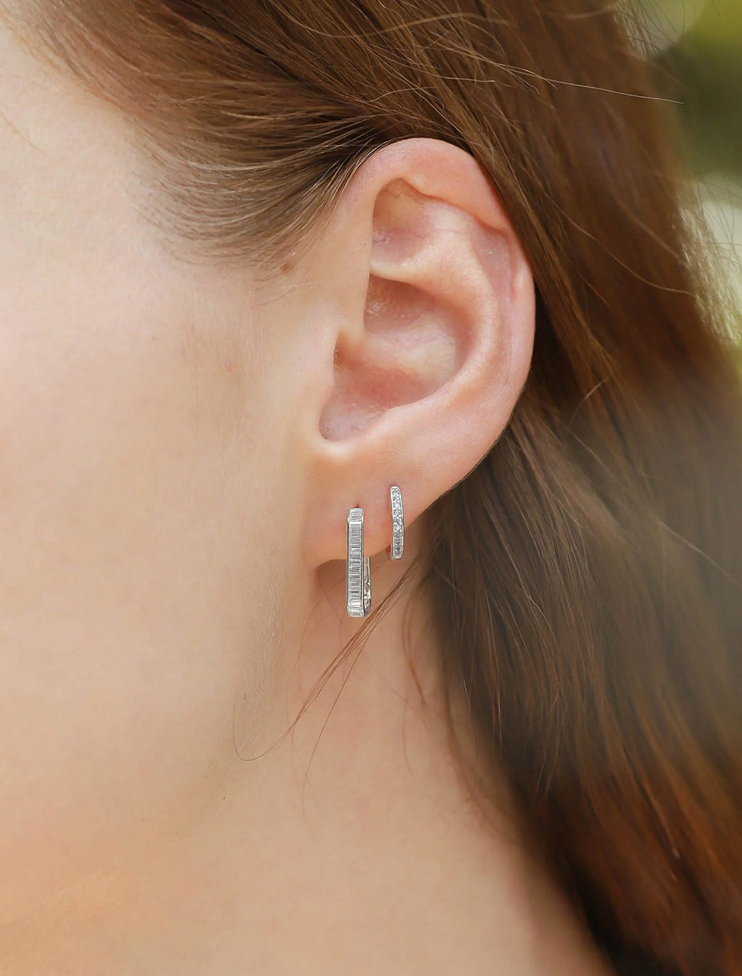Model wearing Tai's oval baguette huggies in silver.