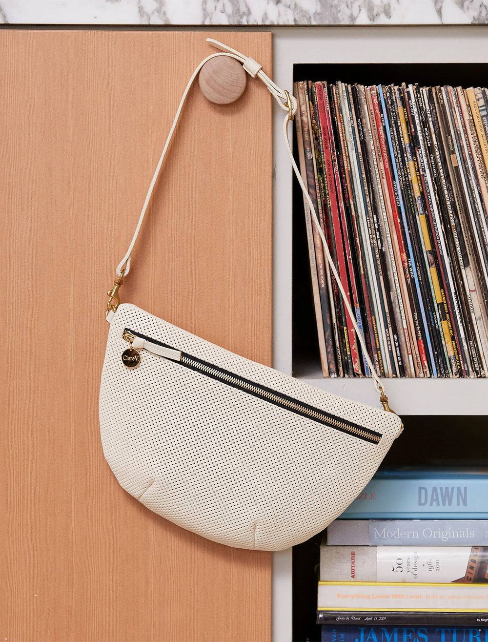 Clare V.'s grande fanny in cream perf hanging on a shelf.